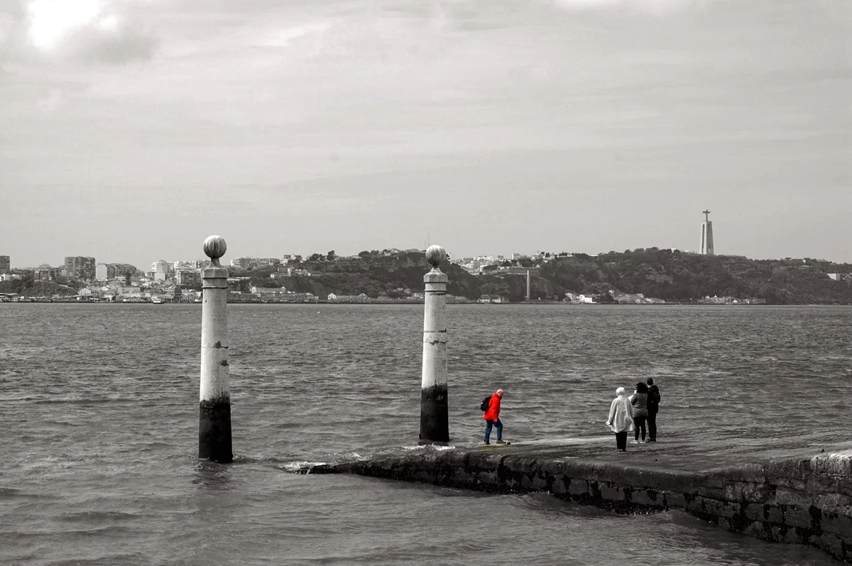 Zona ribeirinha de Lisboa com pessoas junto ao Tejo em contexto urbano