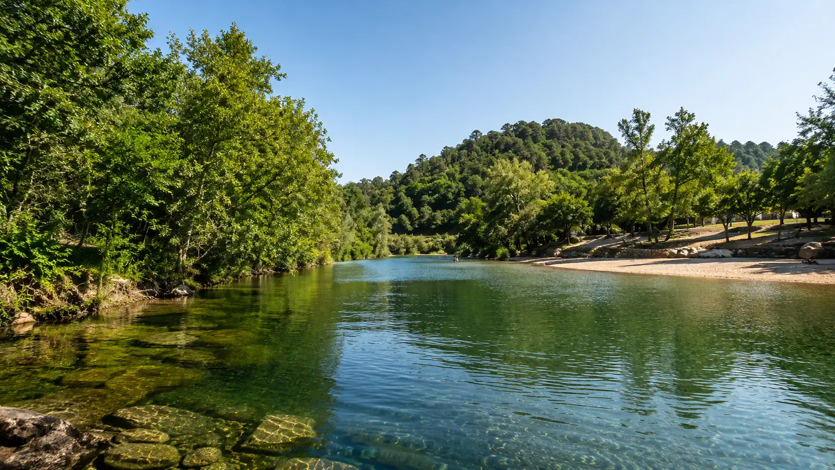 Praia fluvial portuguesa com água calma e zona verde junto à margem