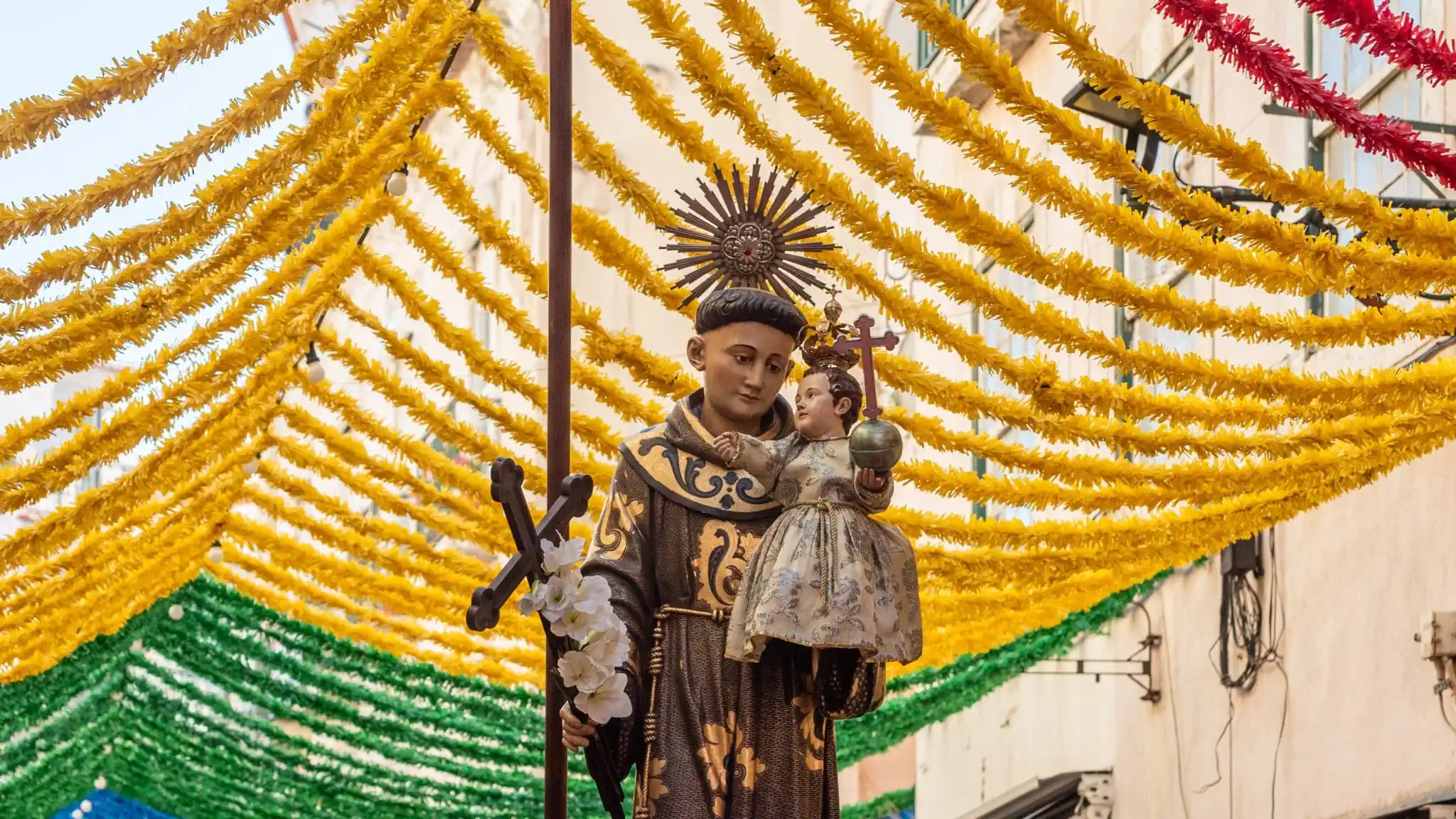Imagem de Santo António durante a procissão numa rua decorada de Lisboa