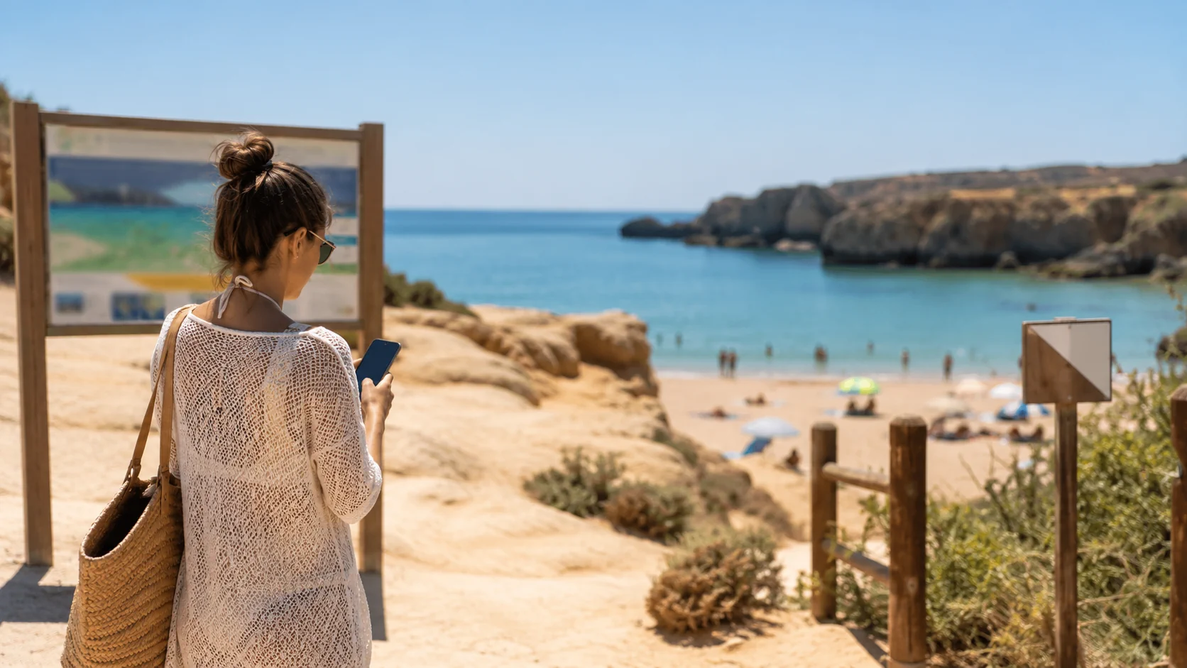Pessoa consulta alertas no telemóvel antes de entrar numa praia portuguesa